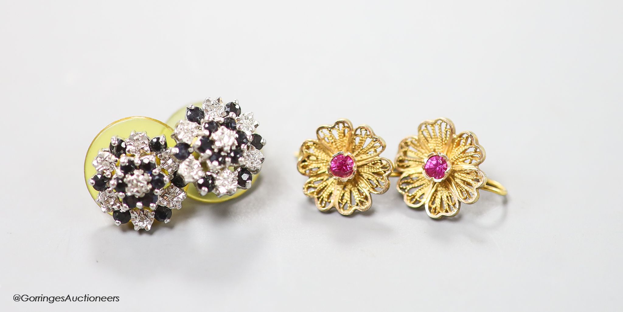 A pair of 9ct sapphire and diamond cluster set ear studs, gross 3.1 grams and a pair of yellow metal and gem set filigree earrings, gross 2.8 grams.